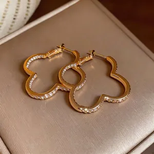 Elegant gold flower-shaped hoop earrings with sparkling cubic zirconia on a luxury jewelry box
