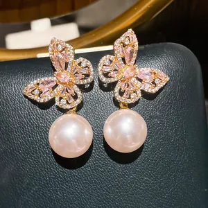 Primo piano degli orecchini a farfalla con zirconi e pendenti di eleganti perle rosa.