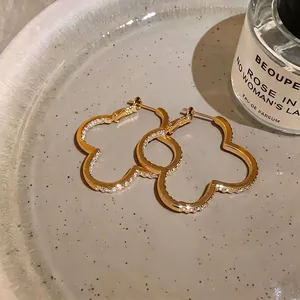 Elegant gold flower-shaped hoop earrings with sparkling zircon inlay on ceramic plate