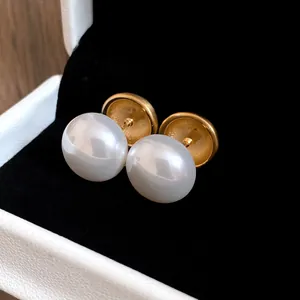 Primo piano di eleganti orecchini tondi in oro spazzolato con grandi perle bianche in scatola