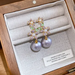 Primo piano di orecchini a fiore in argento con zirconi e pendenti di perle viola