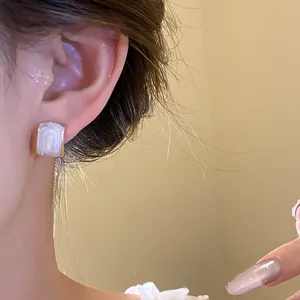 Primo piano dettagliato di un elegante orecchino a bottone quadrato a goccia d'olio