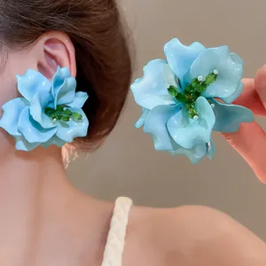 Detailed view of blue acrylic 3D flower earrings with green beaded stamens