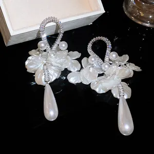 Dettaglio di eleganti orecchini con zirconi e perle a goccia bianche