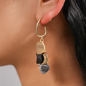 Close-up detail of stylish gold-plated distorted metallic sequin drop earrings for women