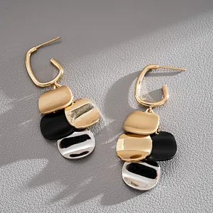 Close-up of gold plated dangling earrings with metallic square sequins and silver pins