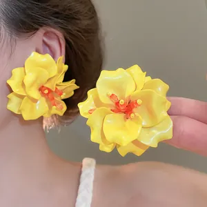 Close-up of vibrant yellow 3D acrylic flower earrings with orange beaded centers on model