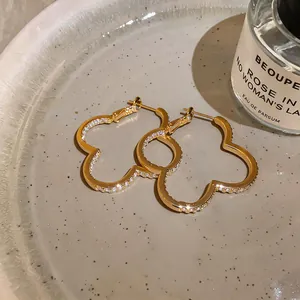 Detailed view of gold flower-shaped hoop earrings with sparkling cubic zirconia stones