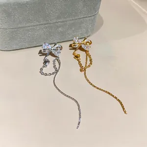 Close-up detail of elegant butterfly bow tassel earrings in gold and silver finish