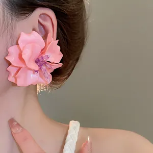 Close-up detail of stylish pink acrylic 3D flower stud earrings worn on a model's ear