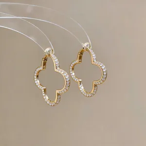 Detailed macro view of gold-tone clover hoop earrings with shimmering zircons
