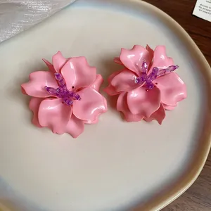 Close-up detail of stylish pink acrylic 3D flower earrings with purple beaded centers