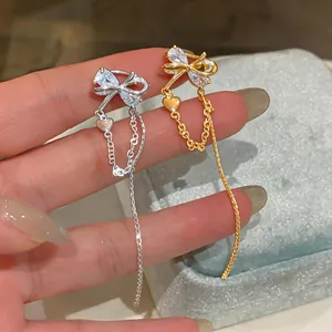 Detail shot of elegant gold and silver bow ear cuffs with long tassel chains on hand