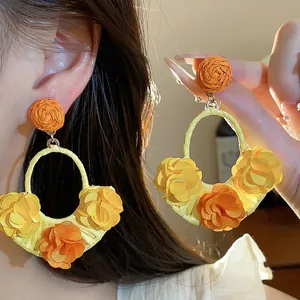 Elegant handmade raffia hoop earrings featuring vibrant yellow and orange fabric flowers
