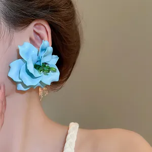 Close-up of an oversized blue 3D acrylic flower earring worn on an ear, seaside style