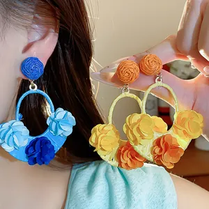 Detailed shot of bohemian raffia fabric flower earrings in blue and yellow colors