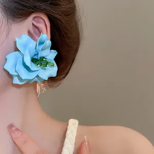 Close-up detail of oversized 3D blue acrylic flower earrings for summer beach trips
