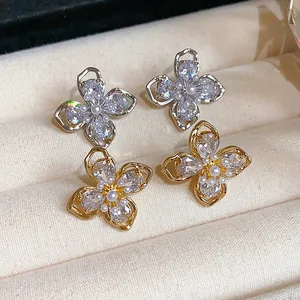Close-up of elegant flower stud earrings with sparkling zircons and white pearls.