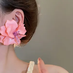 Close-up of pink acrylic 3D flower earring with purple bead stamens on ear.