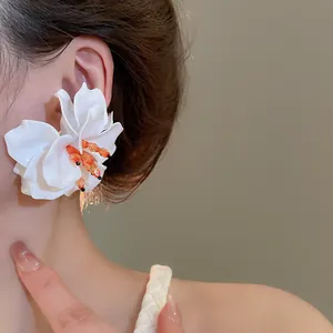 Macro view of a stylish white 3D acrylic flower earring featuring orange beaded stamens