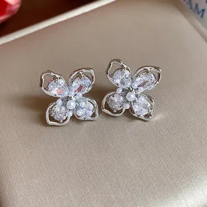 Close-up of four-leaf flower earrings with zircons and pearls on gold display box