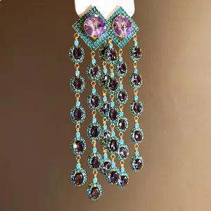 Detailed view of vintage gold tassel earrings with purple crystals and turquoise beads