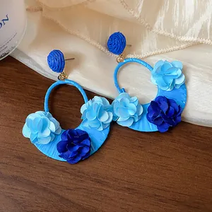 Detailed macro view of blue raffia hoop earrings decorated with fabric flower petals