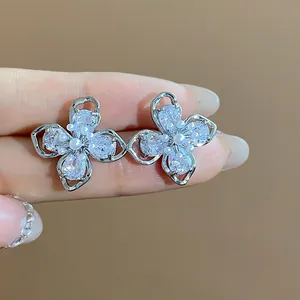 Close-up of elegant flower stud earrings with sparkling zircon petals and central pearl
