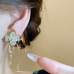 Close-up of elegant 18k gold plated flower stud earrings decorated with zircon and pearls.