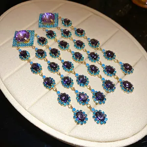Close-up detail of vintage zircon rhombic tassel earrings with purple and turquoise stones