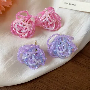 Close-up detail of handmade beaded flower stud earrings in pink and lavender glass beads