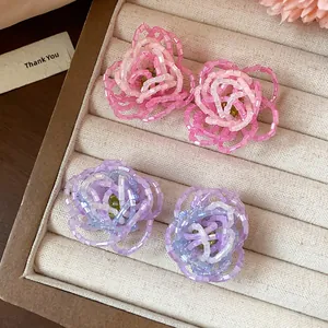 Close-up of elegant beaded flower earrings in pink and lavender floral designs.