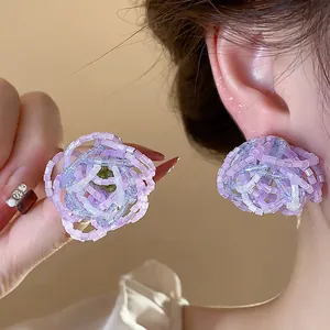Detailed macro view of elegant handmade purple and blue beaded glass flower stud earrings