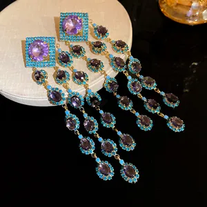 Detailed view of vintage gold tassel earrings featuring purple zircons and turquoise stones