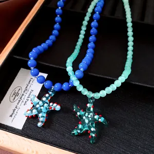 Nahaufnahme von Vintage-Perlenketten mit Seestern-Anhängern aus blauem und grünem Glas.