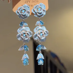 Primo piano dettagliato di orecchini pendenti a rosa blu con cristalli luminosi