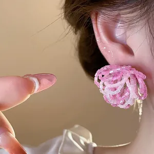 Close-up detail showing a pink glass bead flower stud earring worn on the model's ear