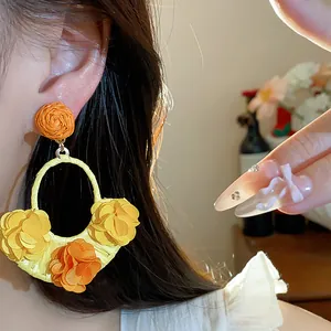 Detailed macro view of bohemian raffia hoop earrings with colorful fabric flowers