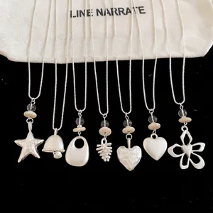 Set of silver geometric pendant necklaces with star, heart, and flower designs.