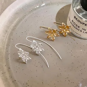 Elegante matte Blumen-Hakenohrringe im Vintage-Stil in Gold und Silber auf einem Keramikteller