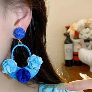Detail of blue raffia fabric flower earring with a chic bohemian resort style design
