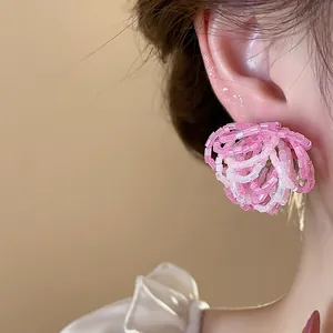 Detailed close-up view of elegant pink glass beaded flower earrings worn on ear
