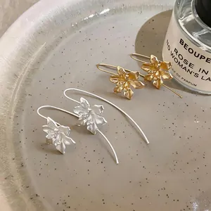 Nahaufnahme von Vintage-Blumenhakenohrringen in Gold- und Silbausführung