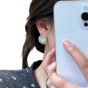 Elegant silver hollow oval stud earrings with crystal inlay shown on model's ear