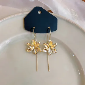 Detailansicht von Retro-Ohrhaken aus Gold in Blumenform mit langem Nadel-Design.