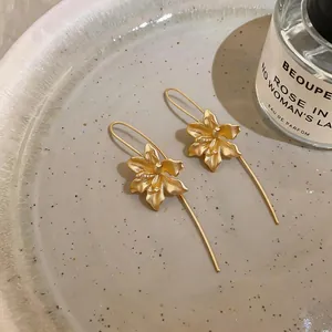 Makro-Detail von vintage mattgoldenen Blumen-Ohrringen mit eleganten Ohrhaken