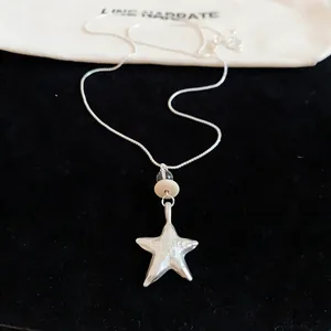 Close-up of silver star pendant necklace with "Promise me" engraving on black velvet.