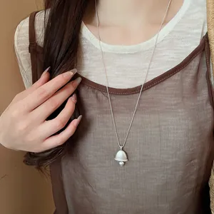 Detail view of a vintage silver bell pendant necklace with heart accent on model