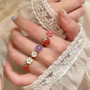 Macro detail showing colorful strawberry and floral enamel rings with gold plating.