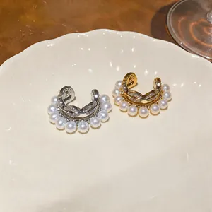 Elegant pearl and zircon ear cuffs displayed on a luxury decorative ceramic plate.